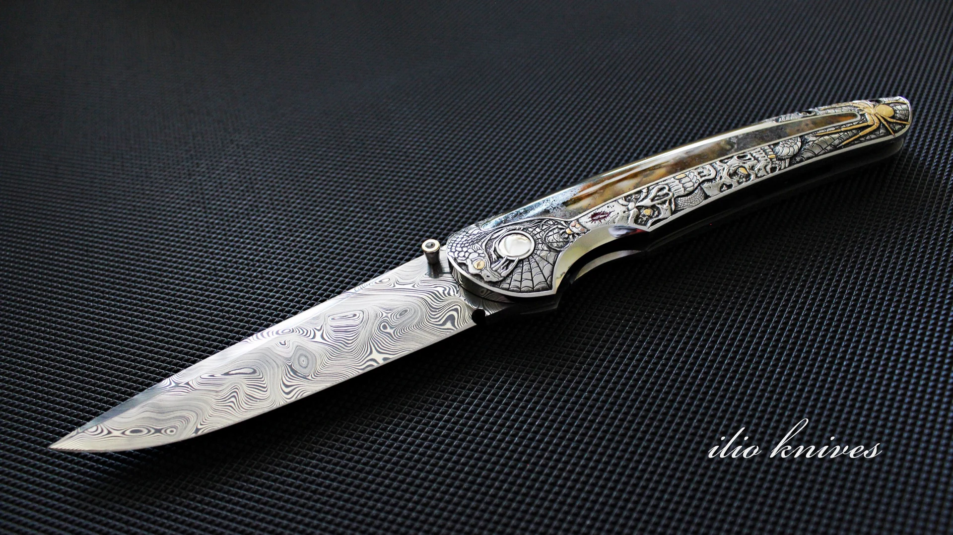 Open Memento Mori folding knife with a patterned Damasteel blade and engraved handle