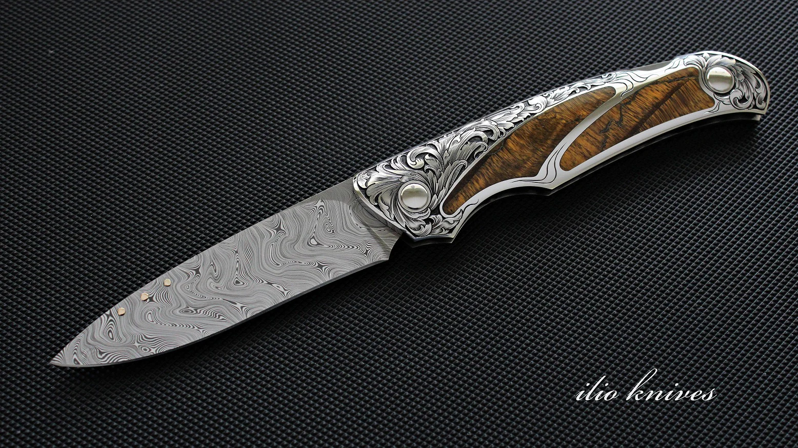 Open Damasteel and Tiger Eye folding knife with engraved handle
