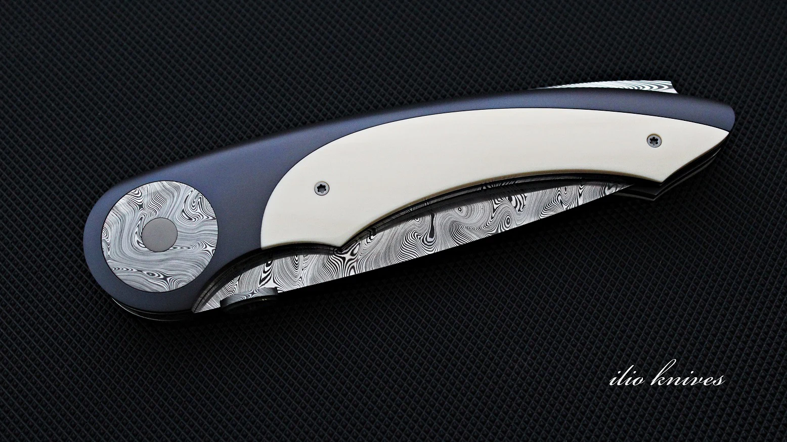 Closed Titanium and Damasteel knife showing ivory scale and anodized titanium